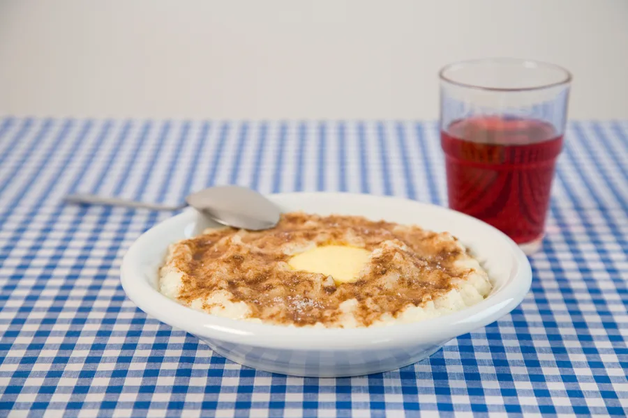 En bolle med grøt med kanel og sukker på en blå og hvit rutete duk