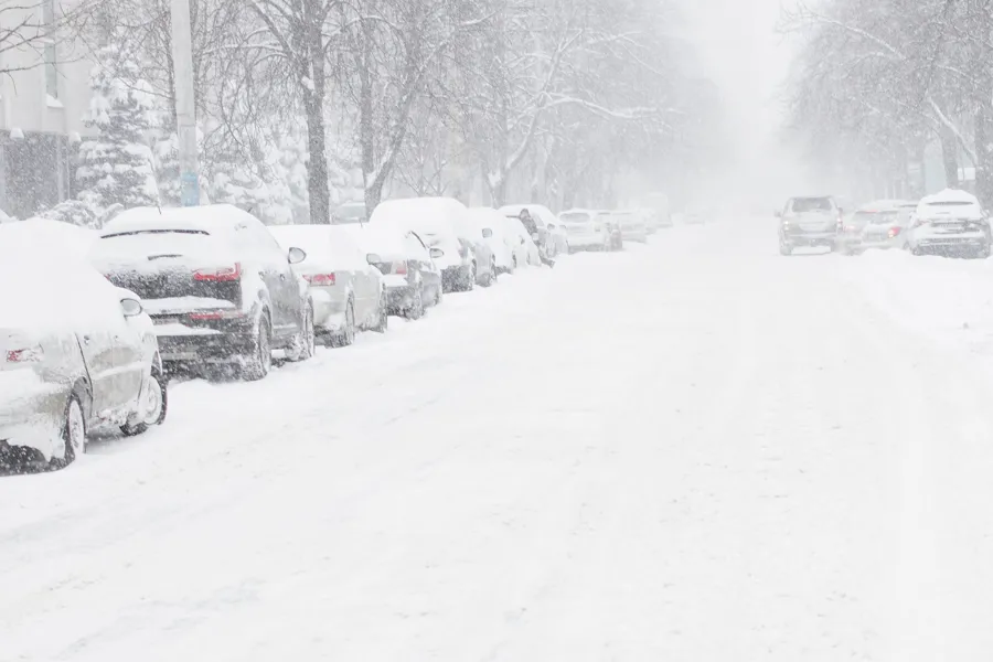 En snødekt gate med biler parkert på siden