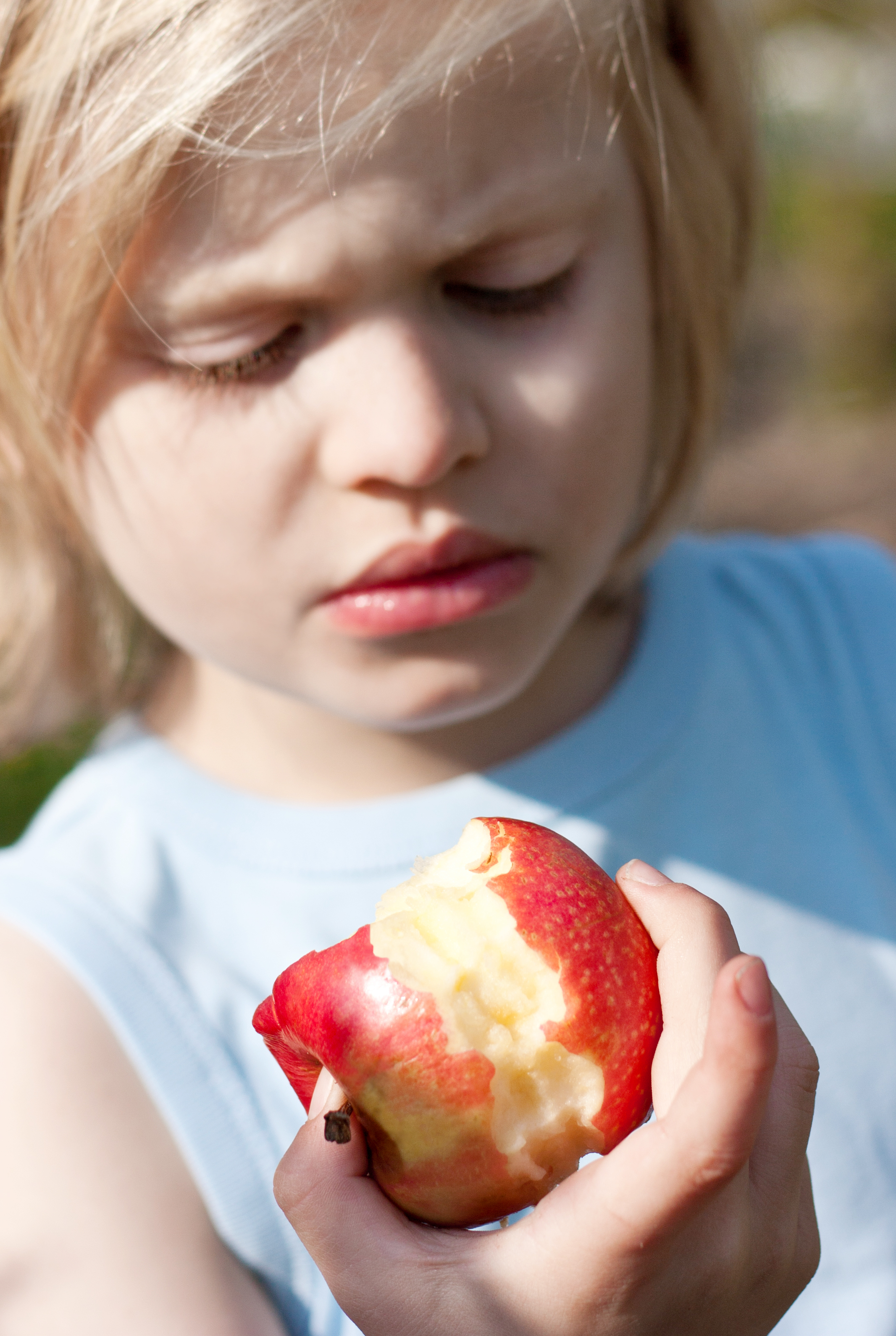 En barn holder et delvis oppspist eple i hånden ute i dagslys