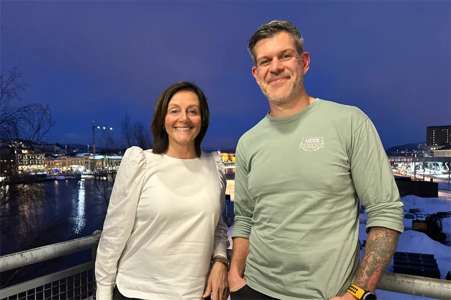 En mann og kvinne som står på en balkong med utsikt over en by om natten