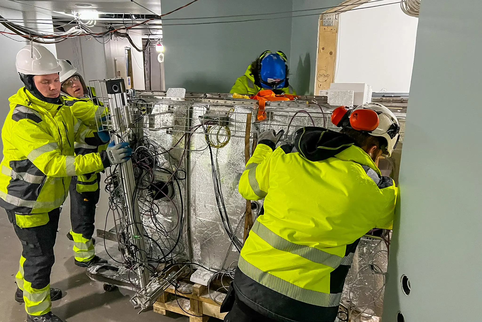 Noen få menn i hjelmer som jobber på en maskin