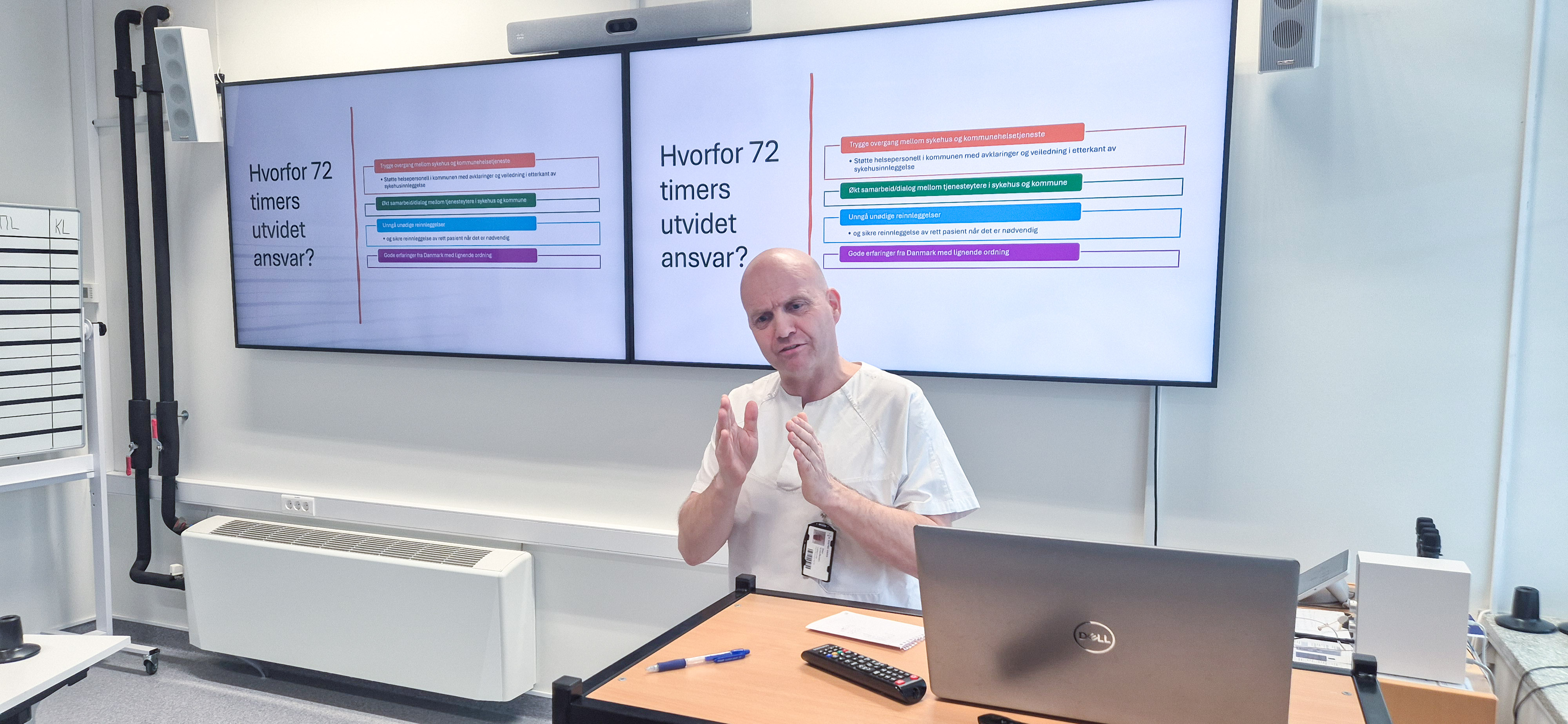 En person som sitter ved et skrivebord foran en projektorskjerm