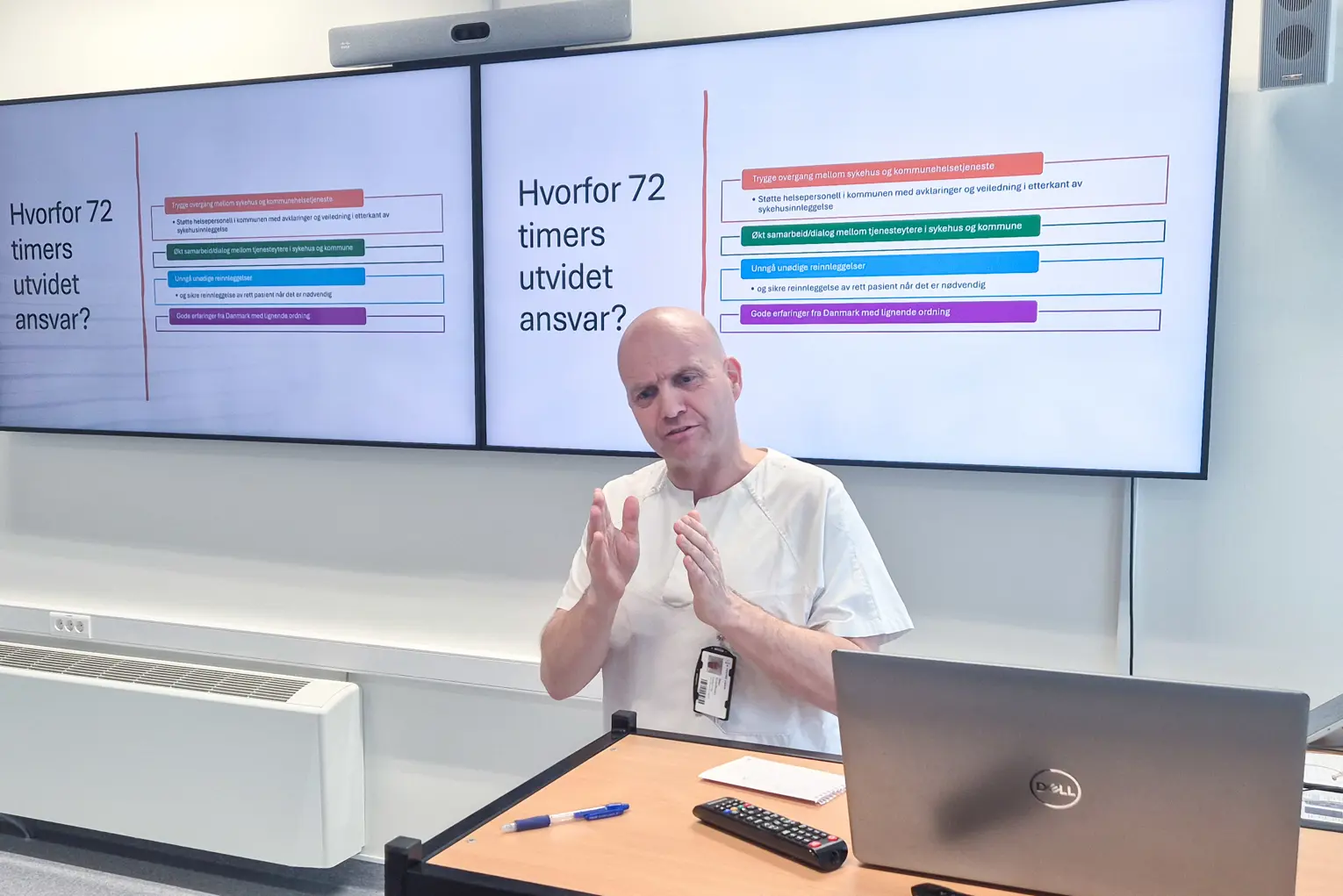 En person som sitter ved et skrivebord foran en projektorskjerm