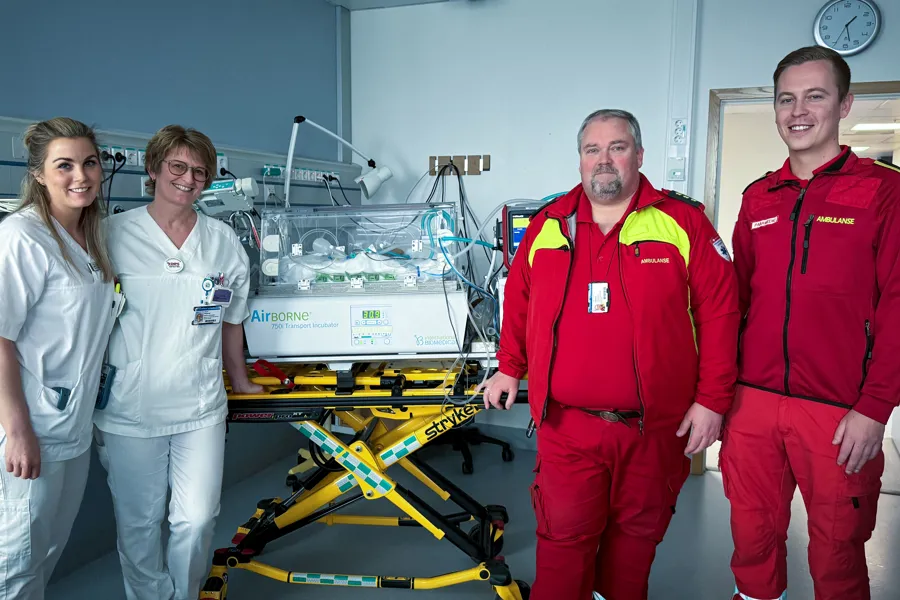 En gruppe mennesker som poserer for et bilde ved siden av en maskin