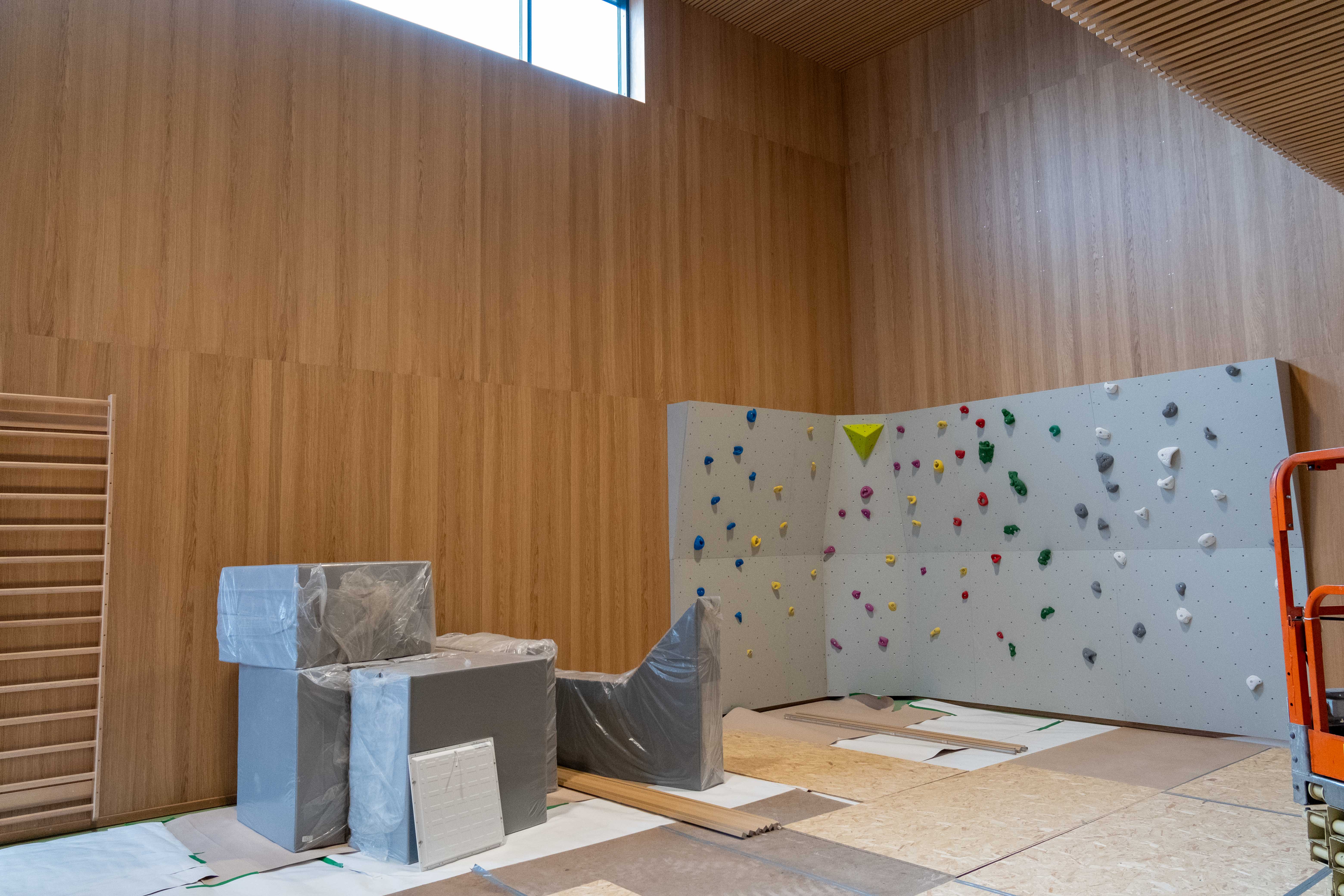 Et rom med en hvit vegg og et tregulv med en hvit og grønn duk og et vindu