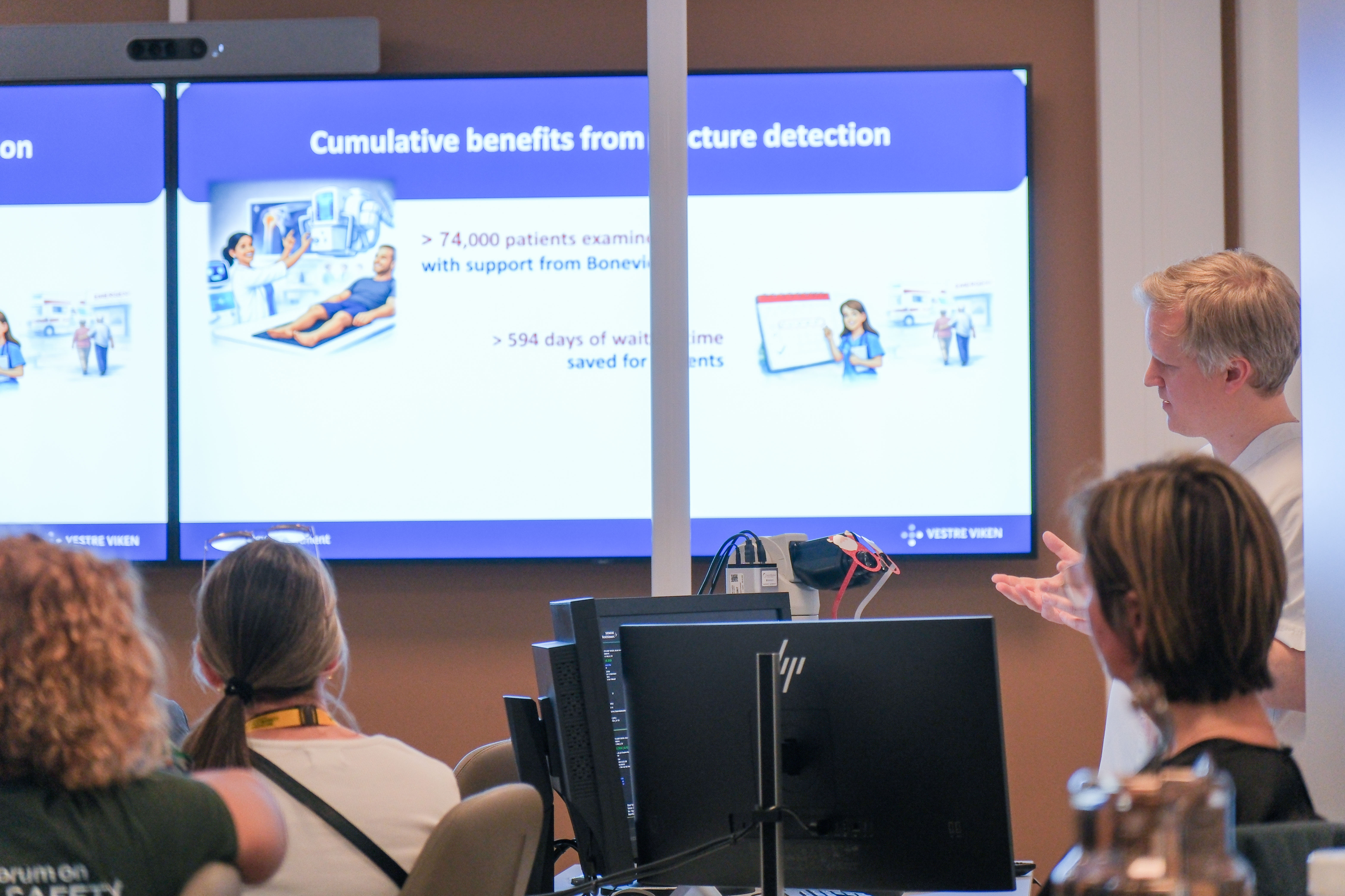 En gruppe mennesker som sitter foran en stor skjerm