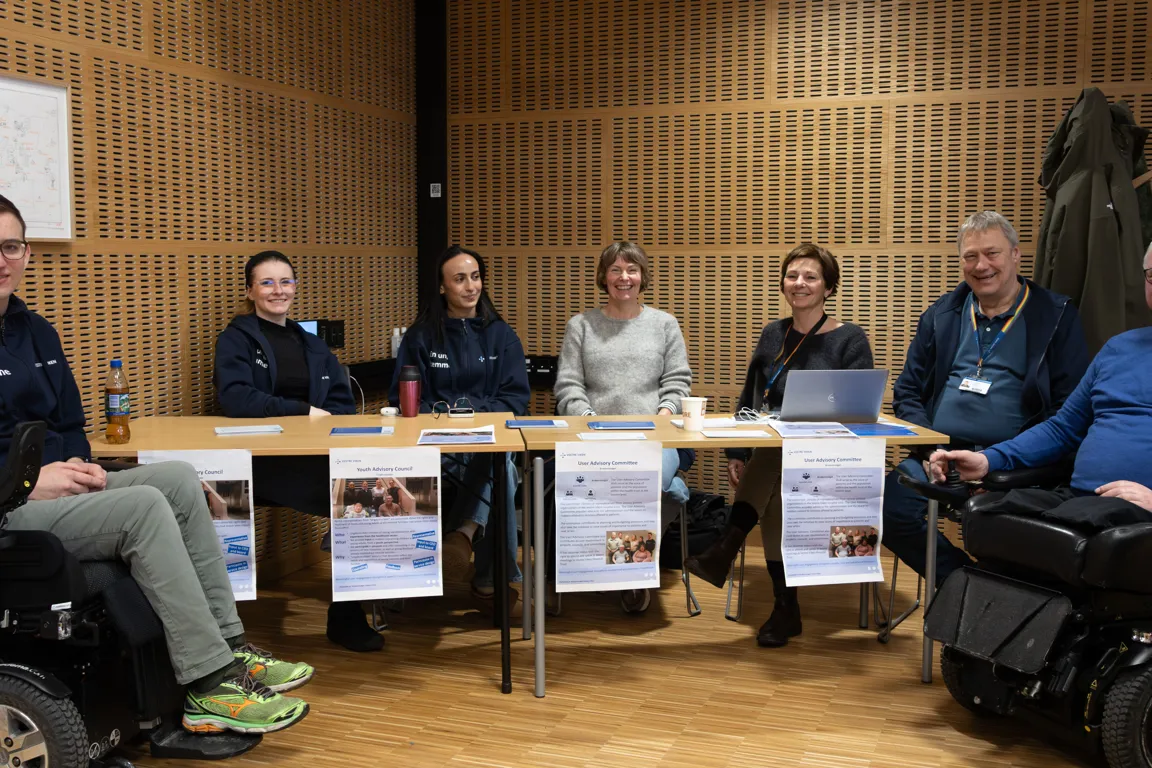 En gruppe mennesker som sitter ved et bord med bærbare datamaskiner