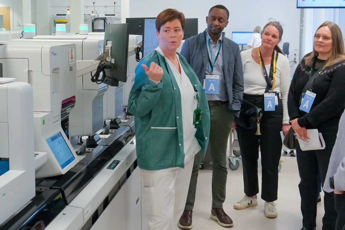 En gruppe mennesker som står ved siden av en skjerm med datamaskiner