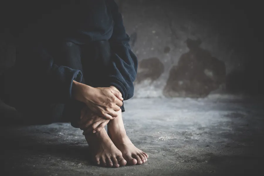 et menneske sitter på gulvet og holder hendene rundt knærne sine