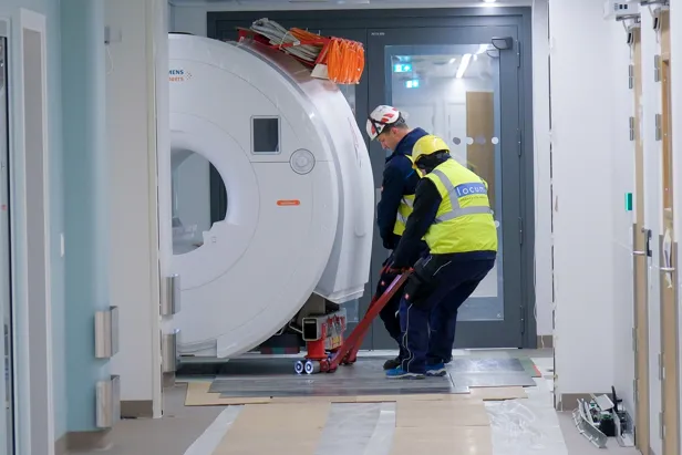 En mann i sikkerhetsvest som bruker en kost til å rengjøre en stor hvit sylinder