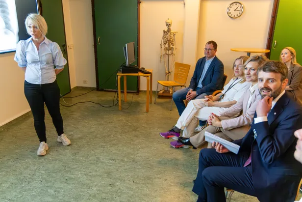 En person som står foran en gruppe mennesker som sitter i stoler