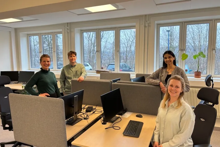 En gruppe mennesker som sitter ved et bord med datamaskiner
