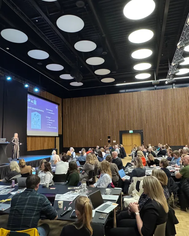 En gruppe mennesker som sitter i et konferanserom