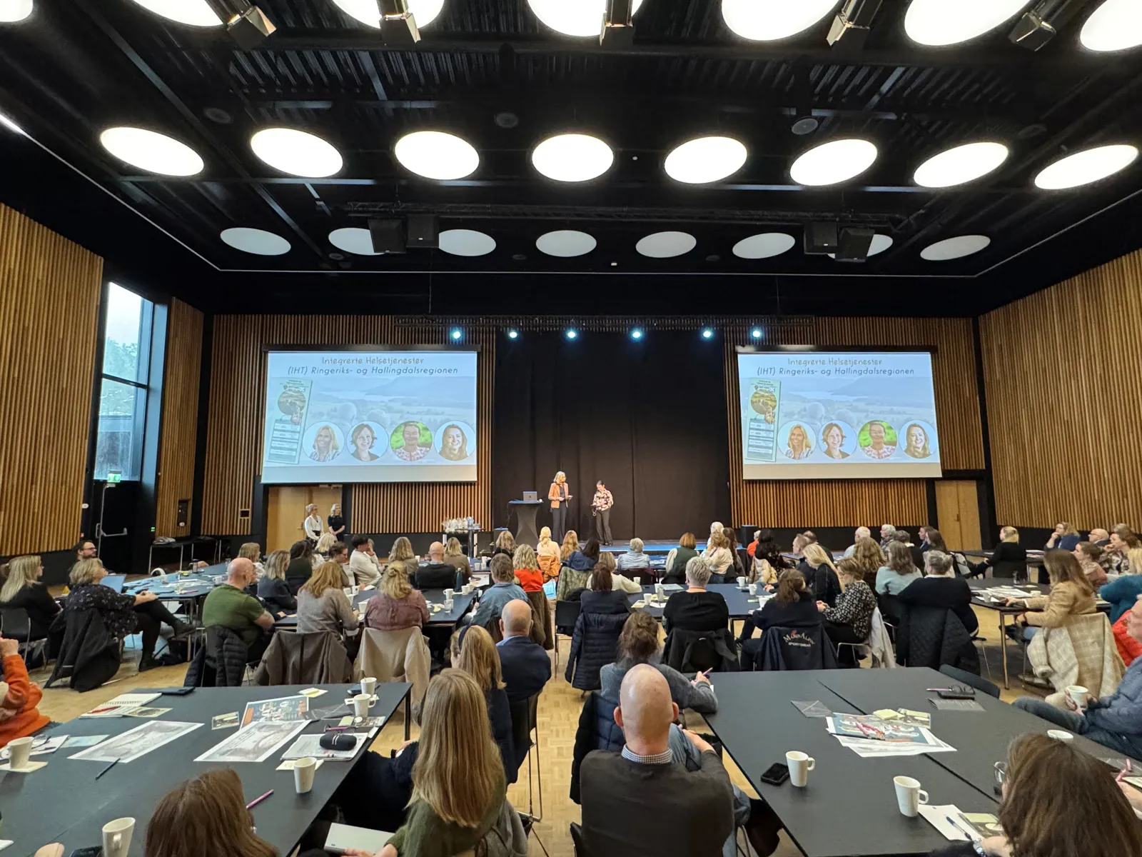 En gruppe mennesker som sitter i et rom med en stor skjerm