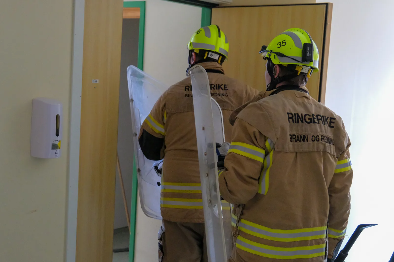 Brannmenn i verneutstyr i et rom