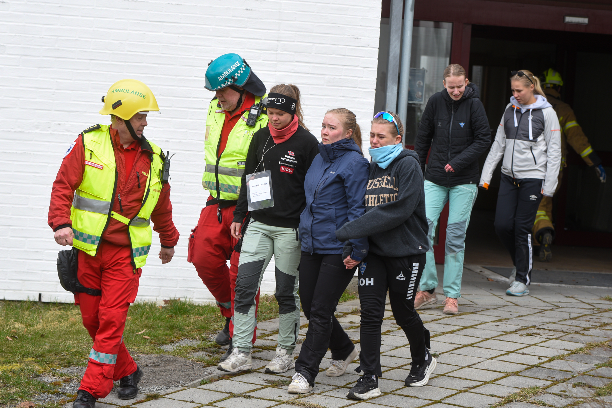En gruppe mennesker med vernevester som står utenfor en bygning