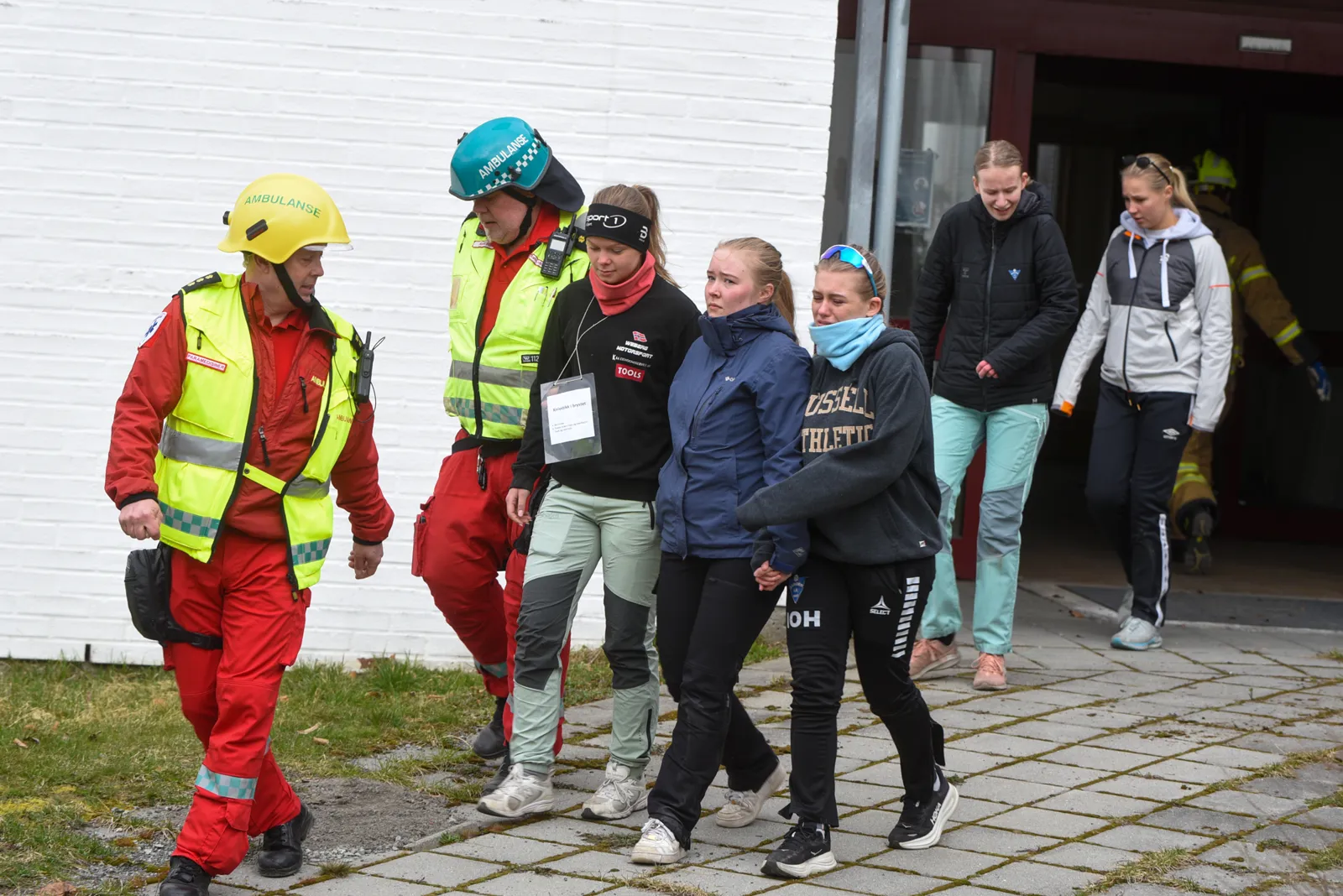 En gruppe mennesker med vernevester som står utenfor en bygning