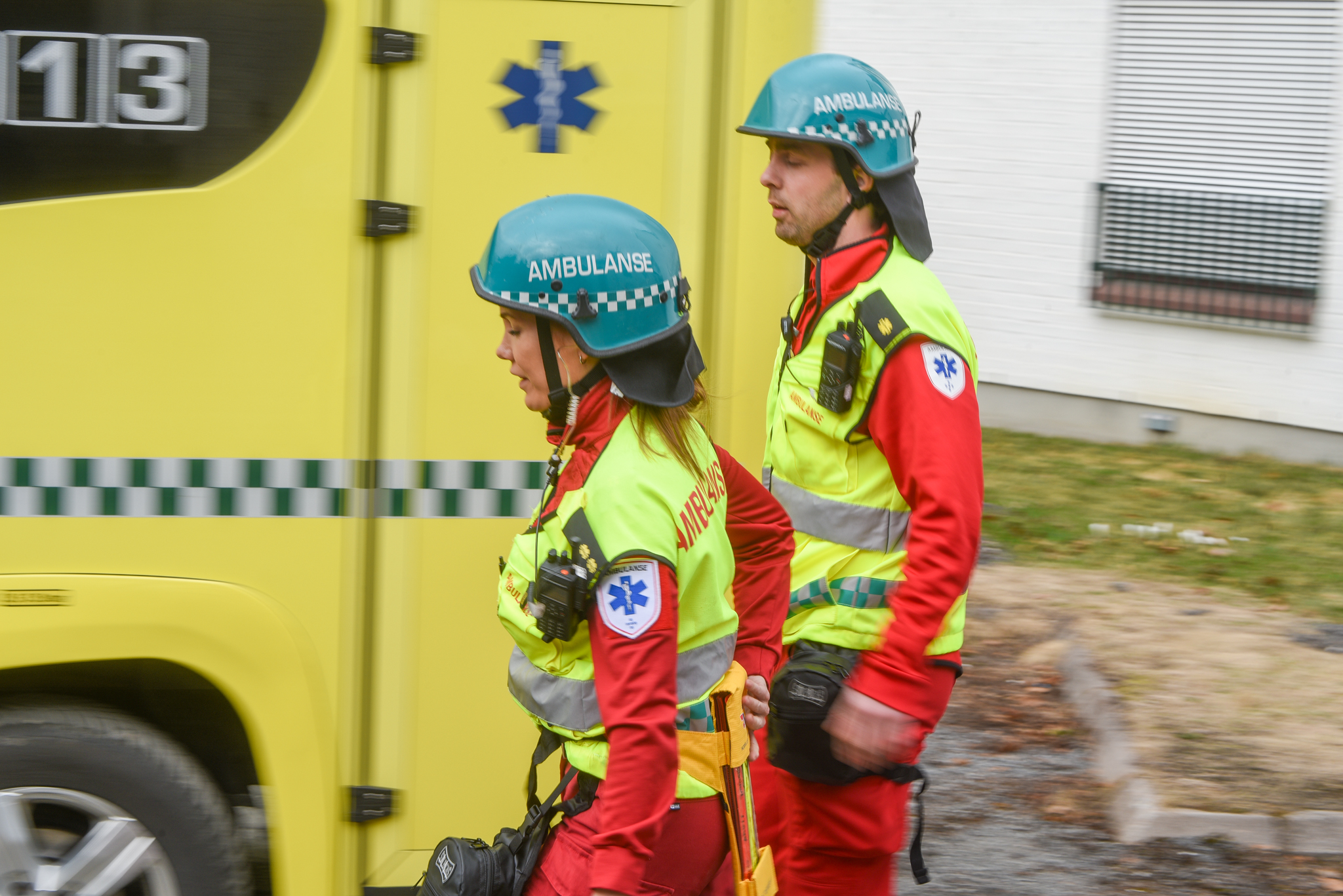 Et par brannmenn foran en gul brannbil