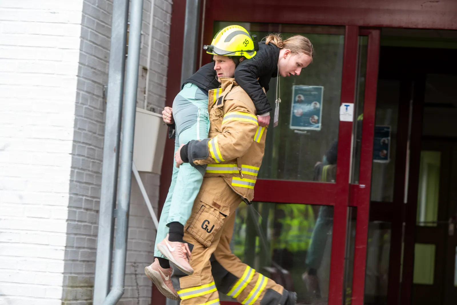 En person som holder et barn på ryggen til en brannmann