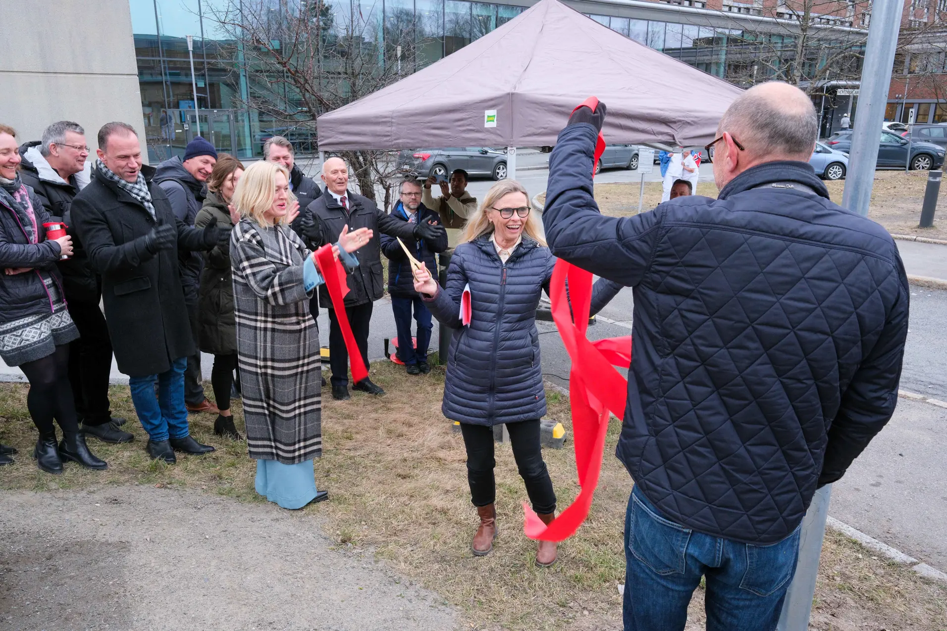 En person som holder et rødt bånd foran en mengde mennesker