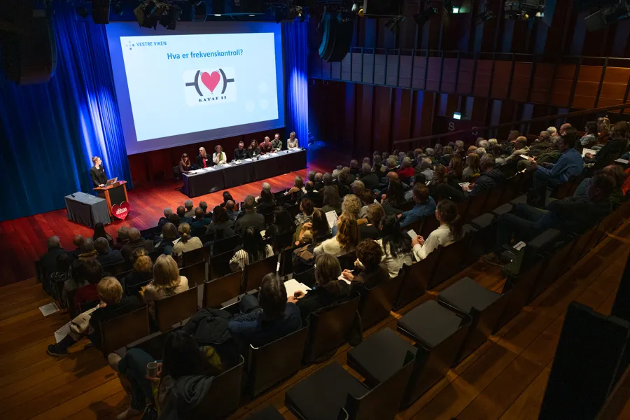 En gruppe mennesker som sitter i et rom med en stor skjerm