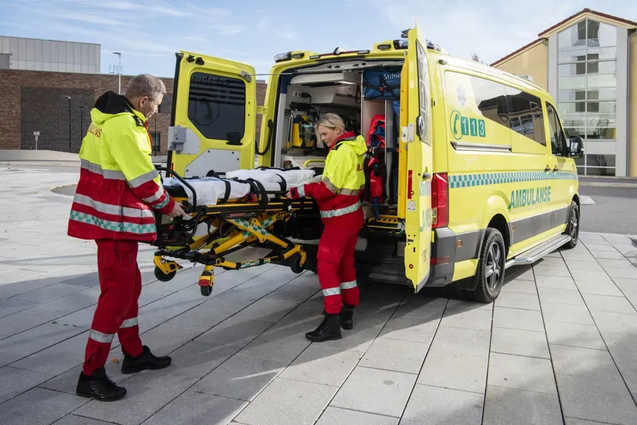 Et par menn i oransje jumpsuits som står ved siden av en gul lastebil