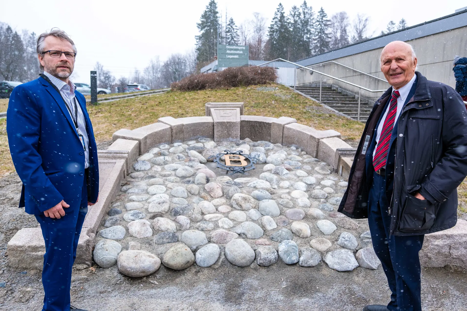 Et par menn som står ved siden av en steinkonstruksjon med en steinmur