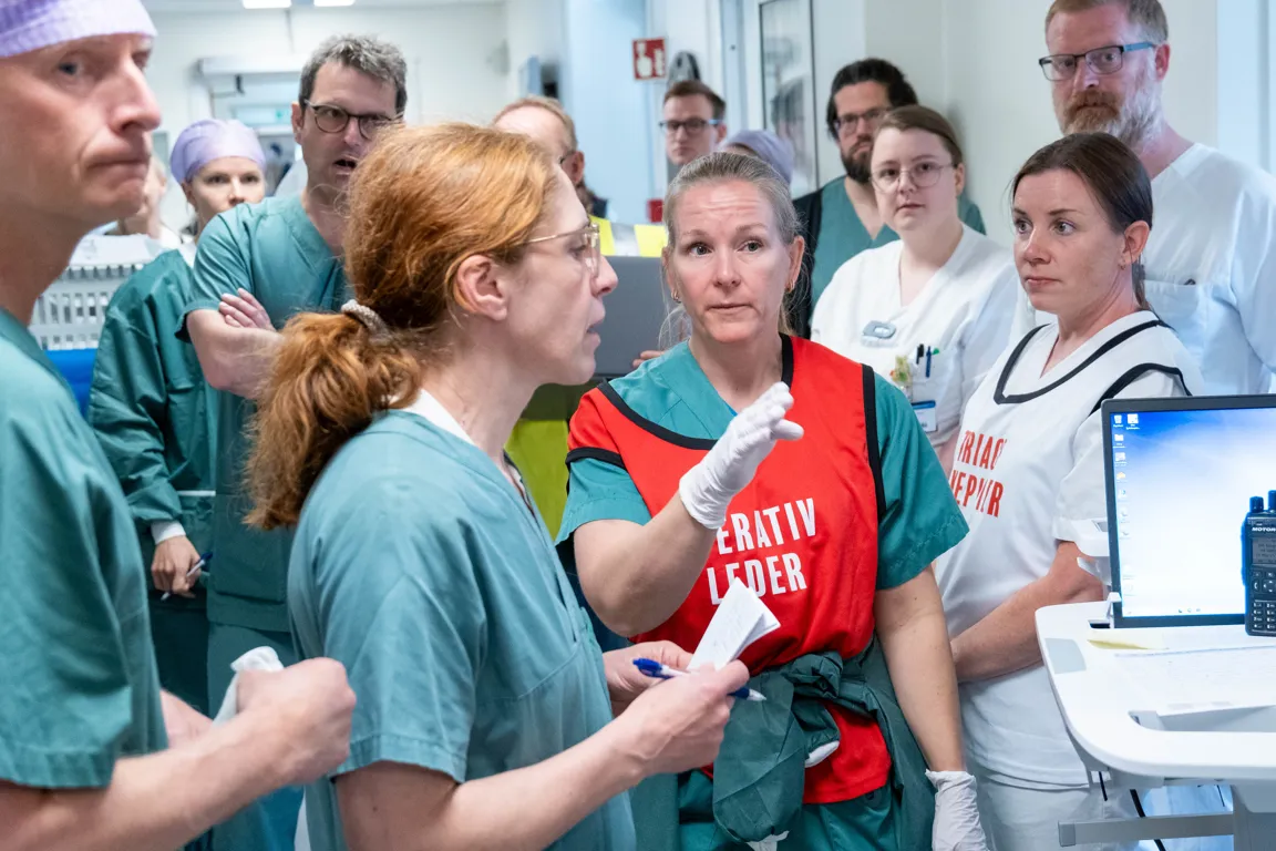 En gruppe mennesker som står rundt en mann som holder en mikrofon