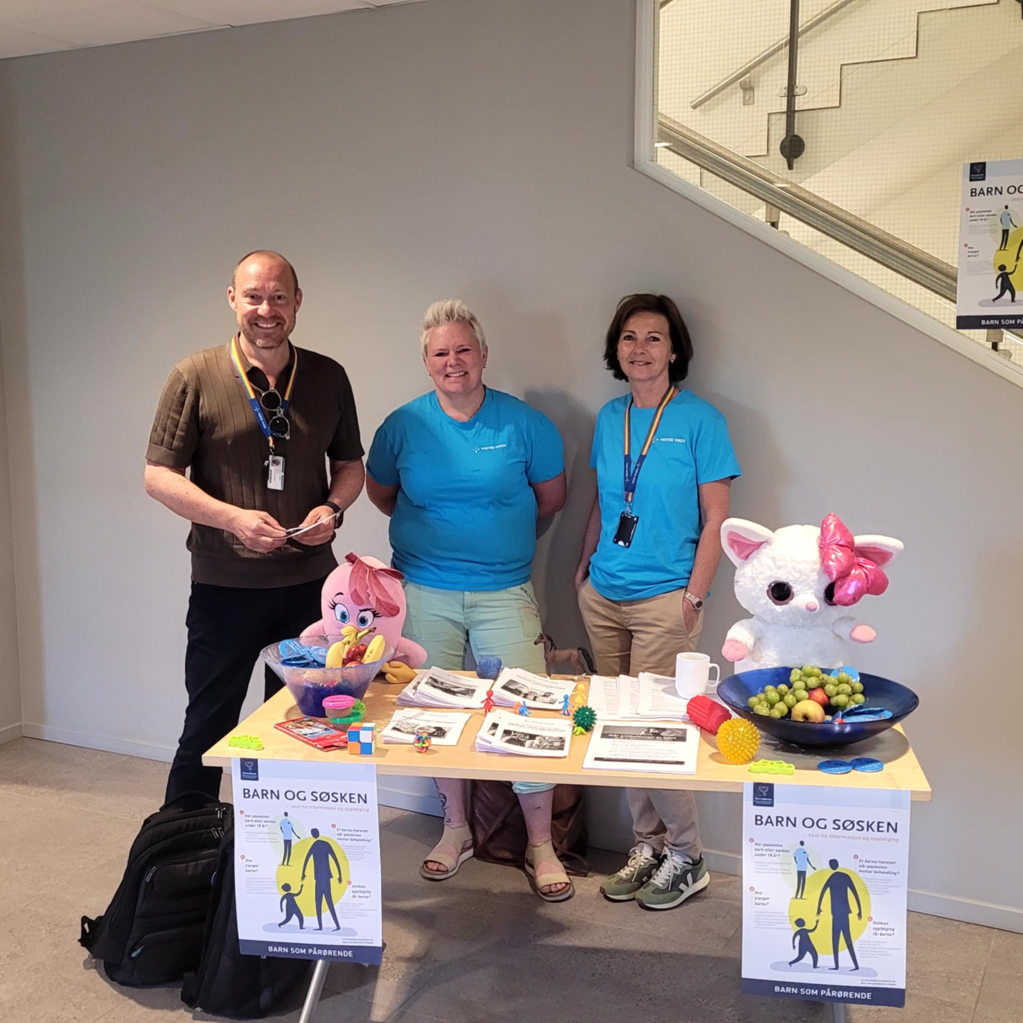 En gruppe mennesker som står ved siden av et bord med mat og drikke