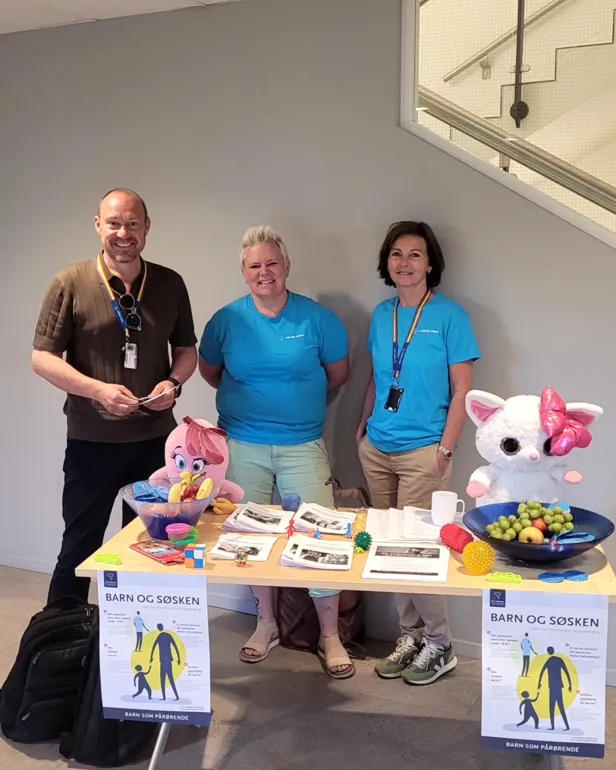 En gruppe mennesker som står ved siden av et bord med mat og drikke