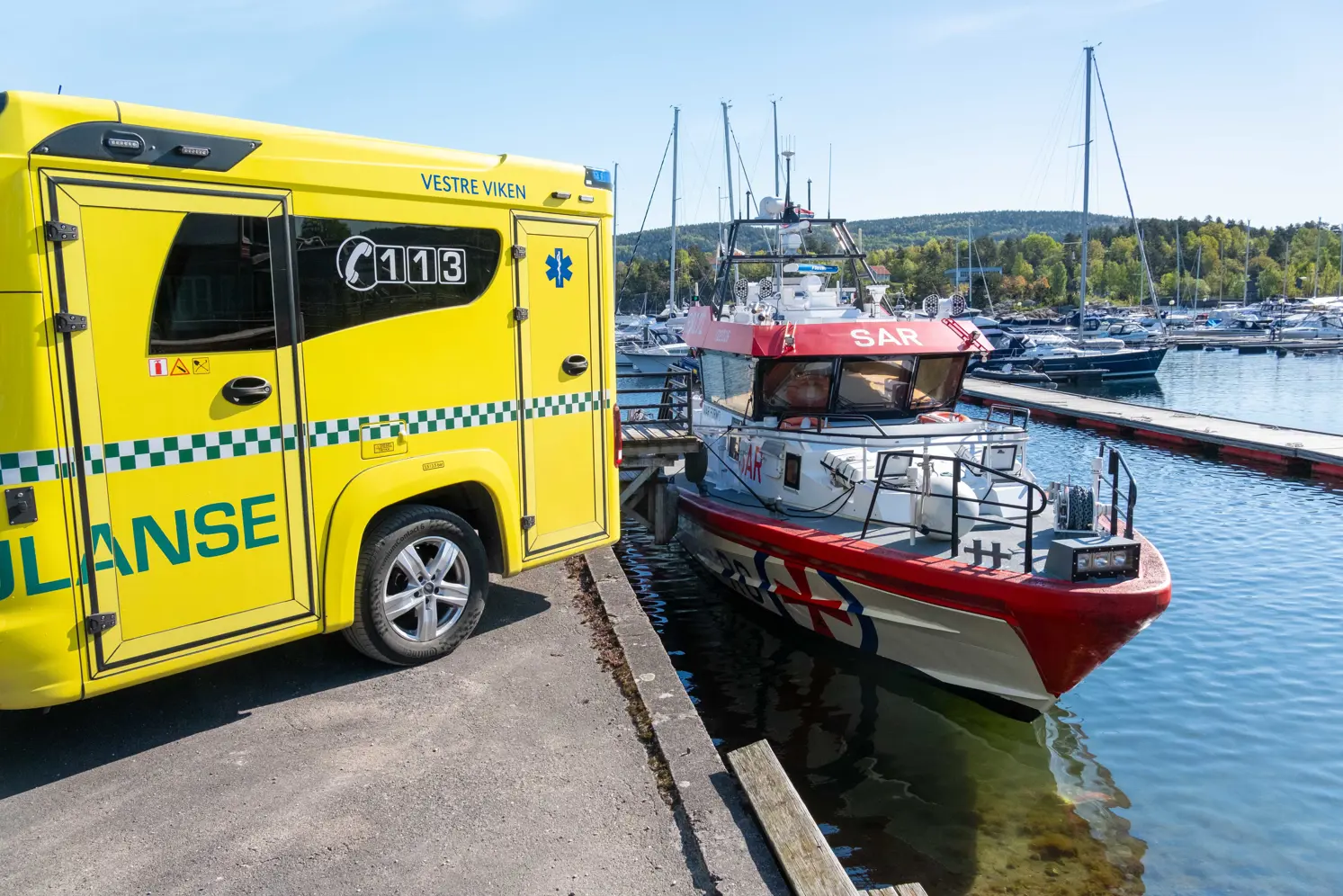 En gul lastebil parkert ved siden av en båt på en brygge