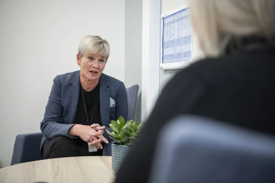 En kvinne i dress som snakker med en annen kvinne i dress