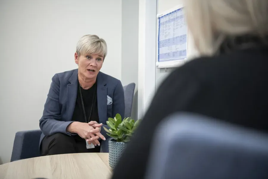 En kvinne i dress som snakker med en annen kvinne i dress