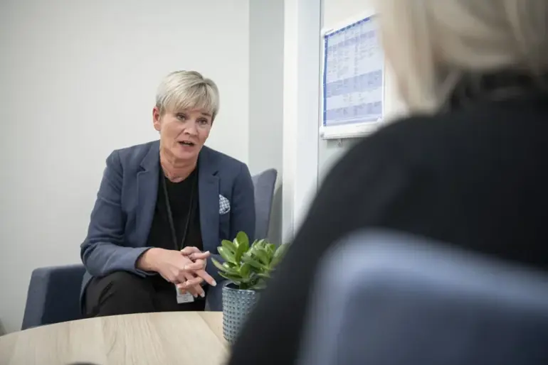 En kvinne i dress som snakker med en annen kvinne i dress
