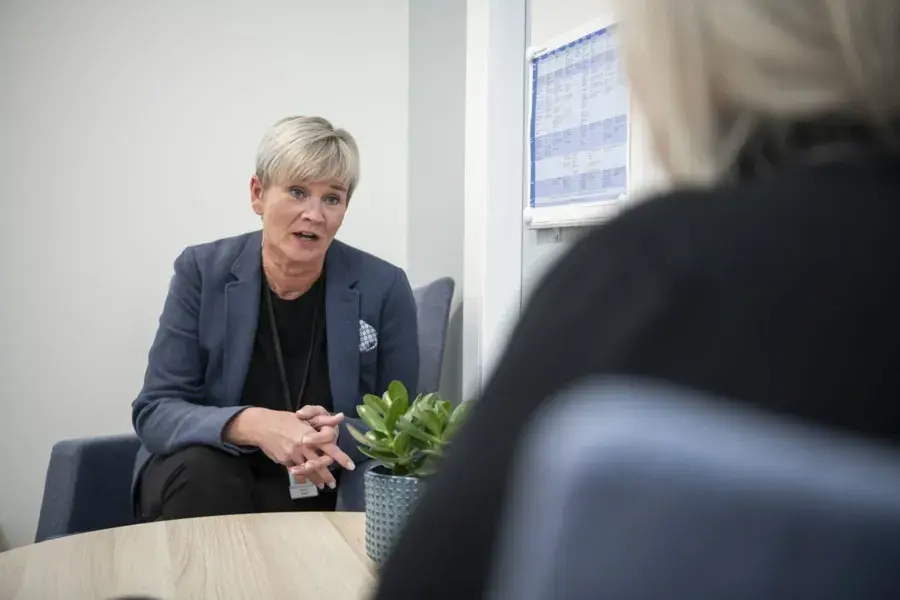 En kvinne i dress som snakker med en annen kvinne i dress