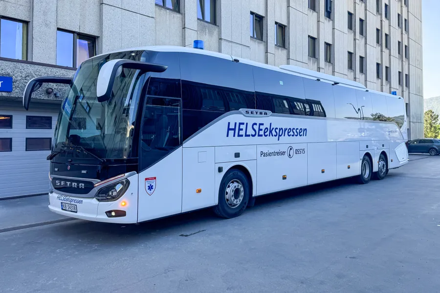 En hvit buss parkert i veikanten