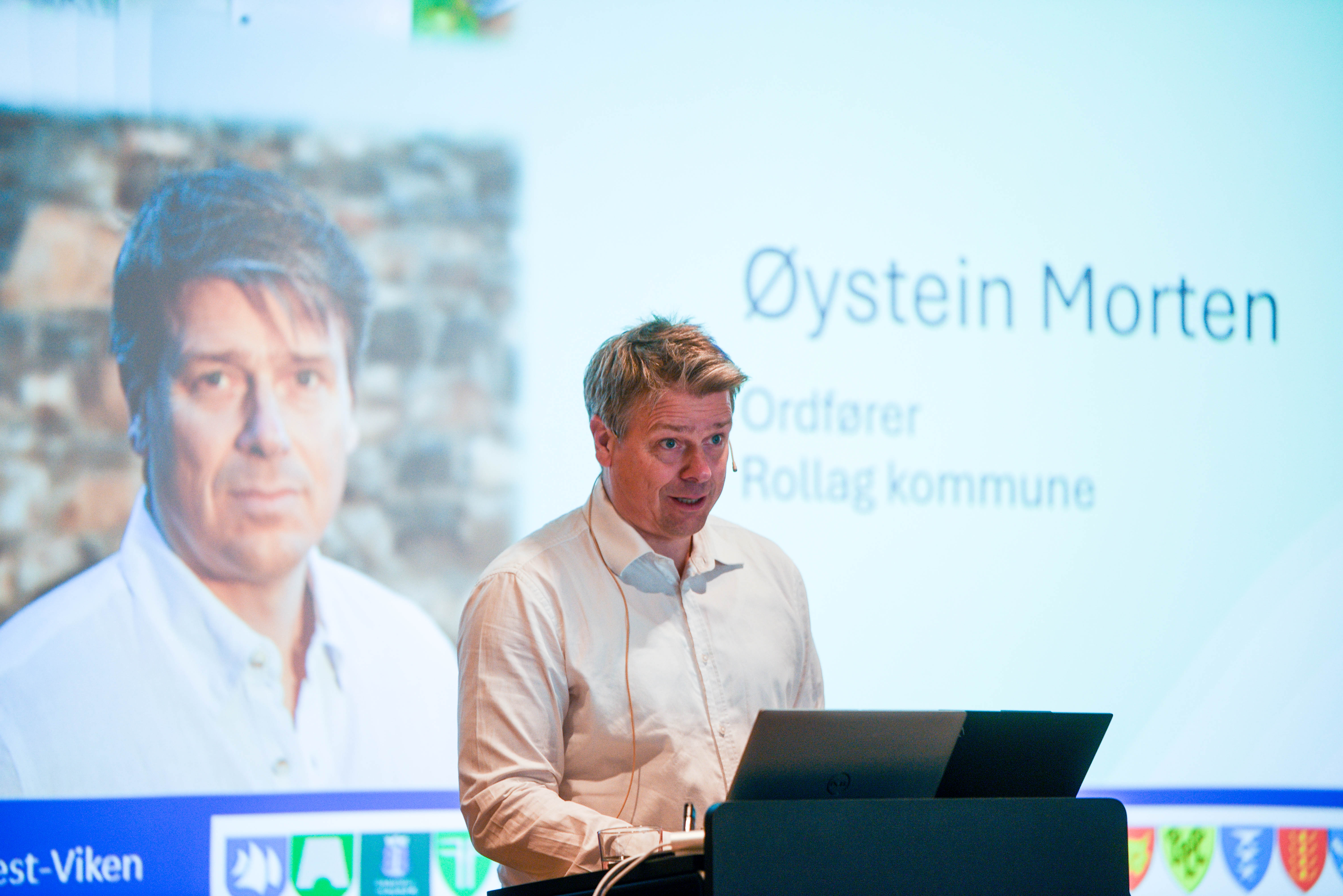 En mann som står ved siden av en mann som sitter ved et skrivebord