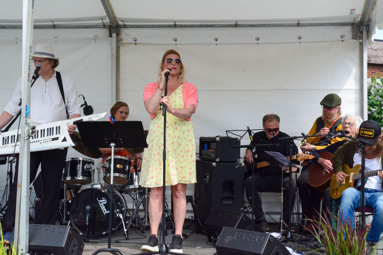 En person som synger inn i en mikrofon foran et band som spiller instrumenter
