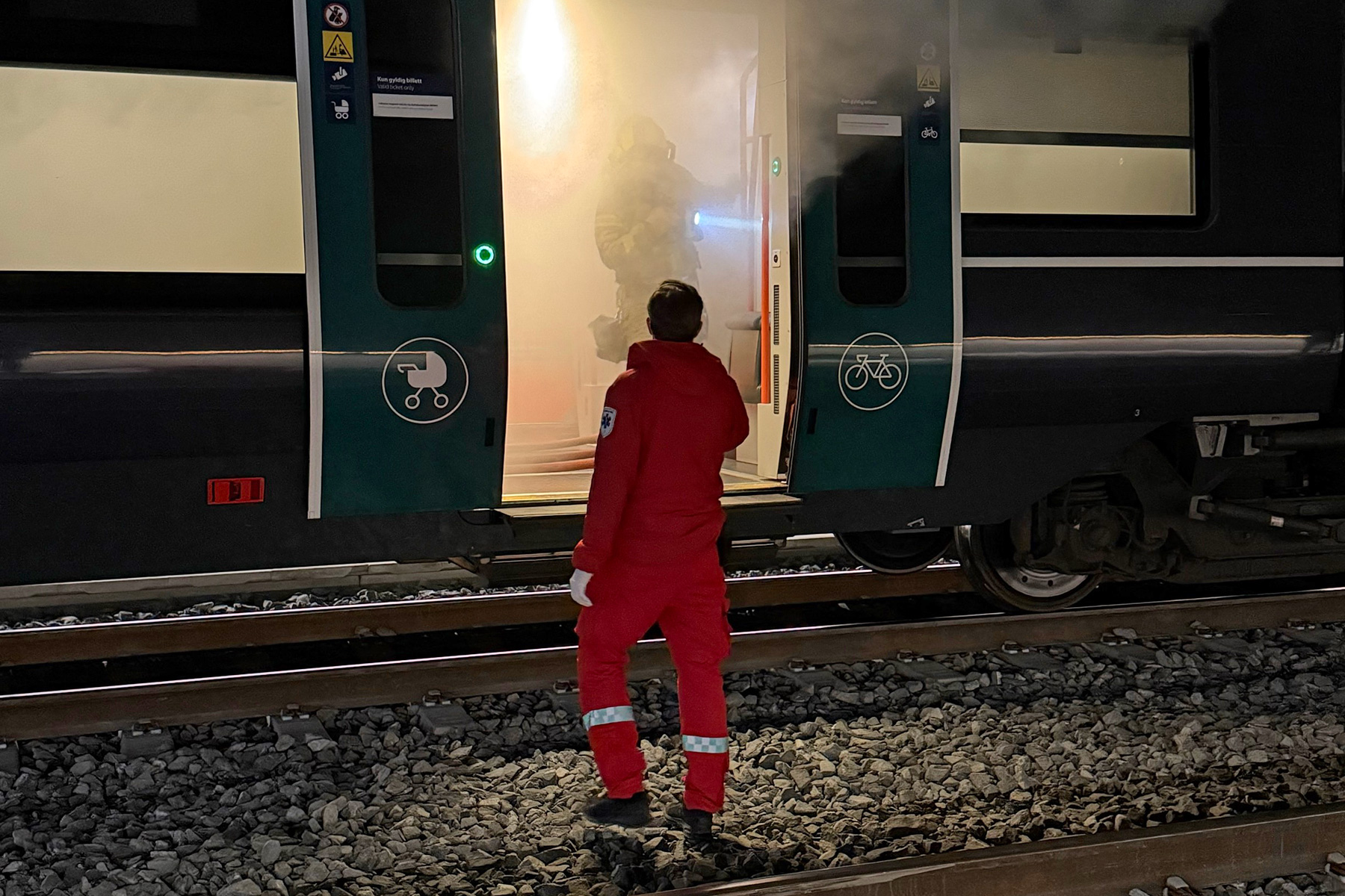 En mann i rød dress som står på en togskinne