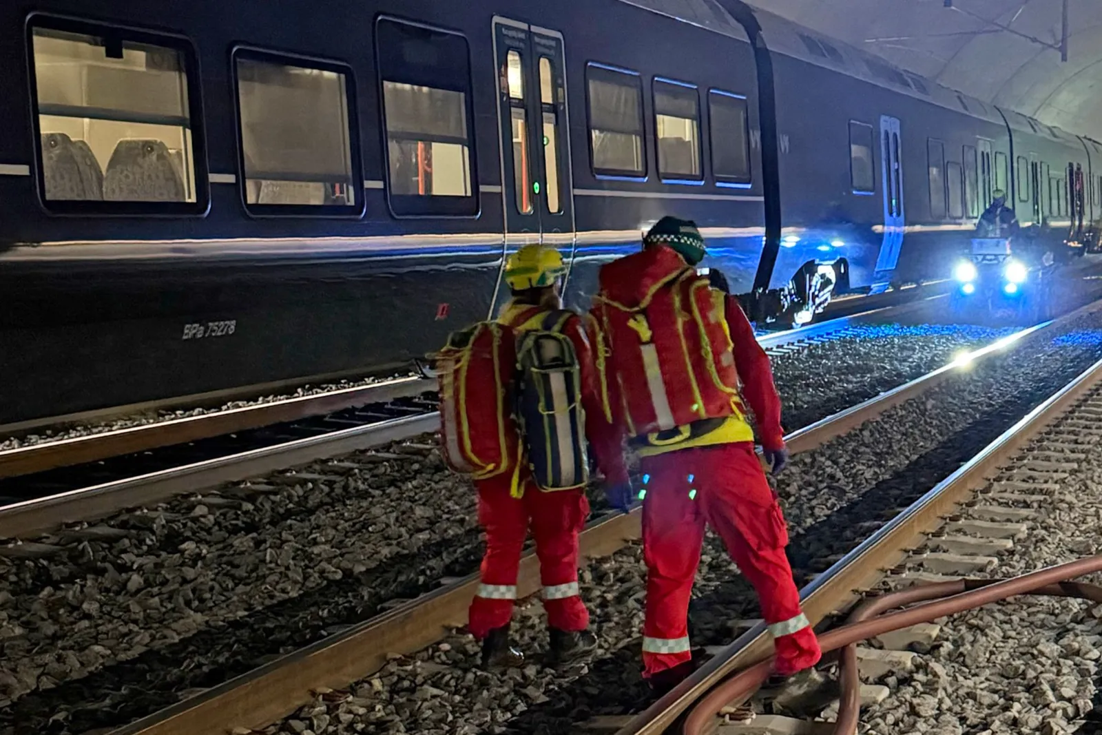 Noen få menn i sikkerhetsvester som står på togskinnene