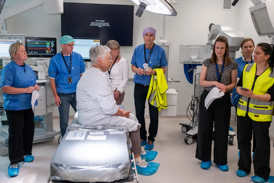 En gruppe mennesker som står rundt en person i en sykehusseng