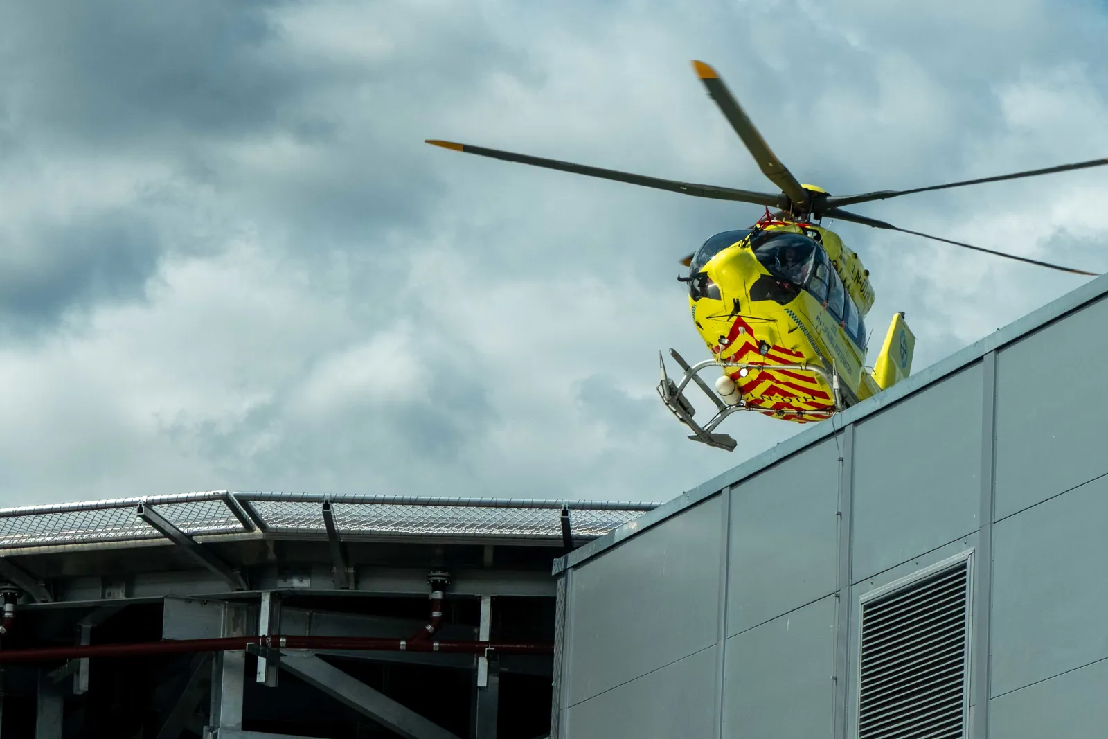 A yellow helicopter flying over a building