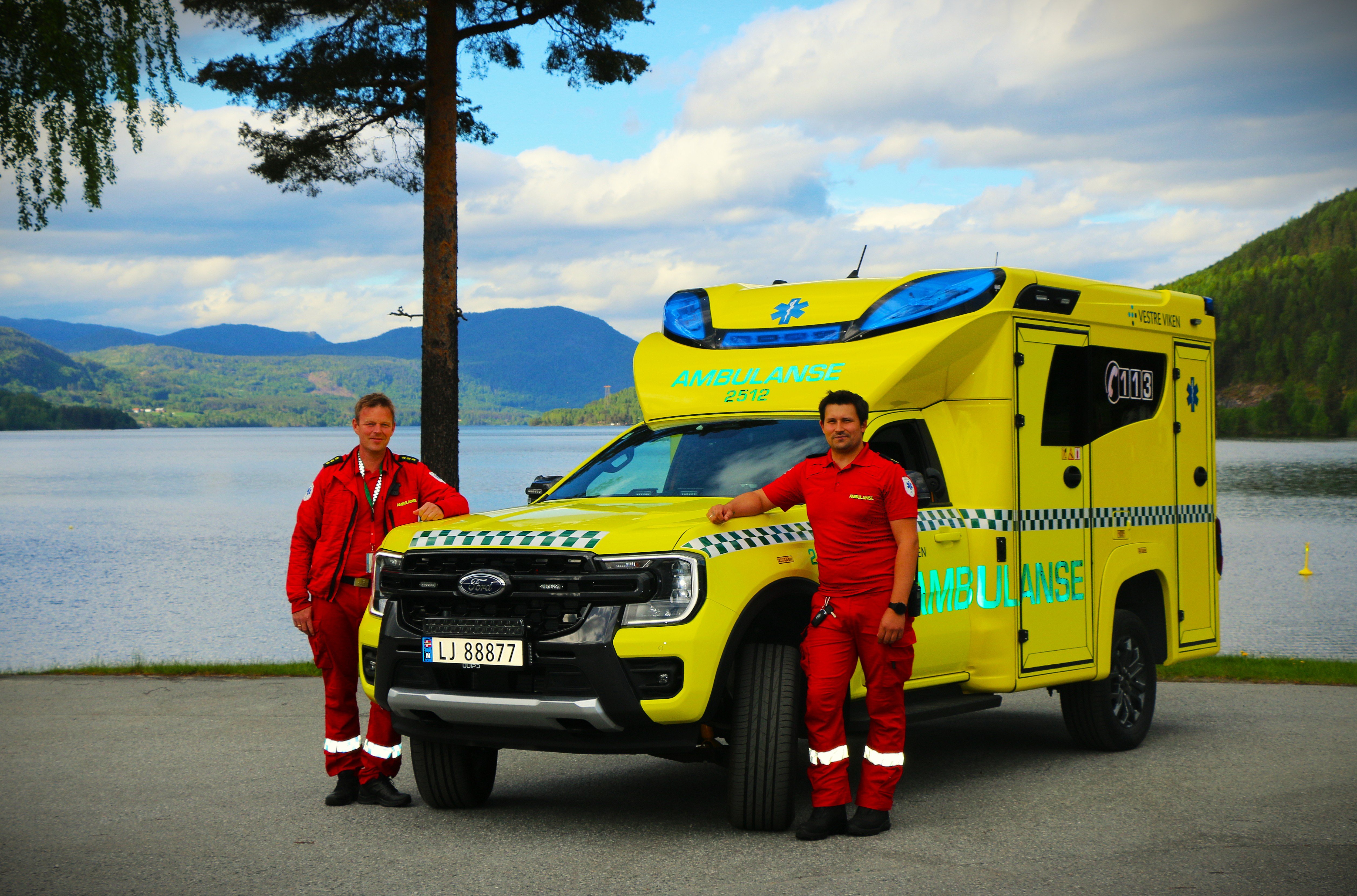 To menn står ved siden av en gul bil med blå og rød stripe