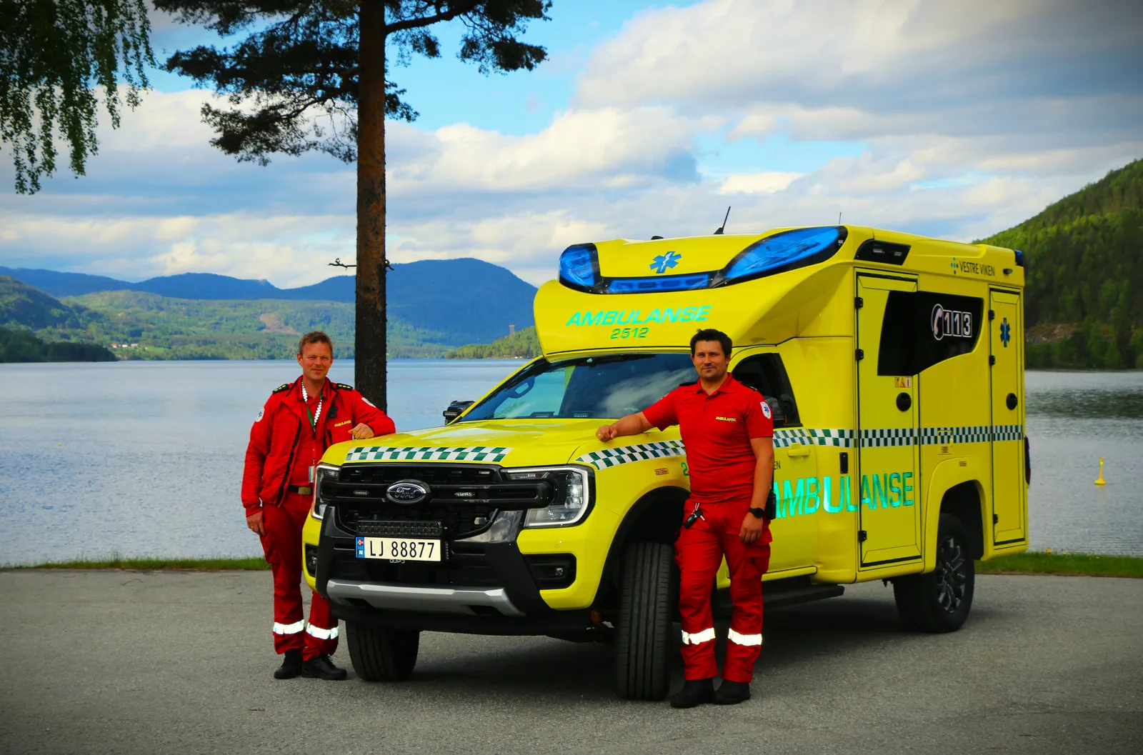 To menn står ved siden av en gul bil med blå og rød stripe