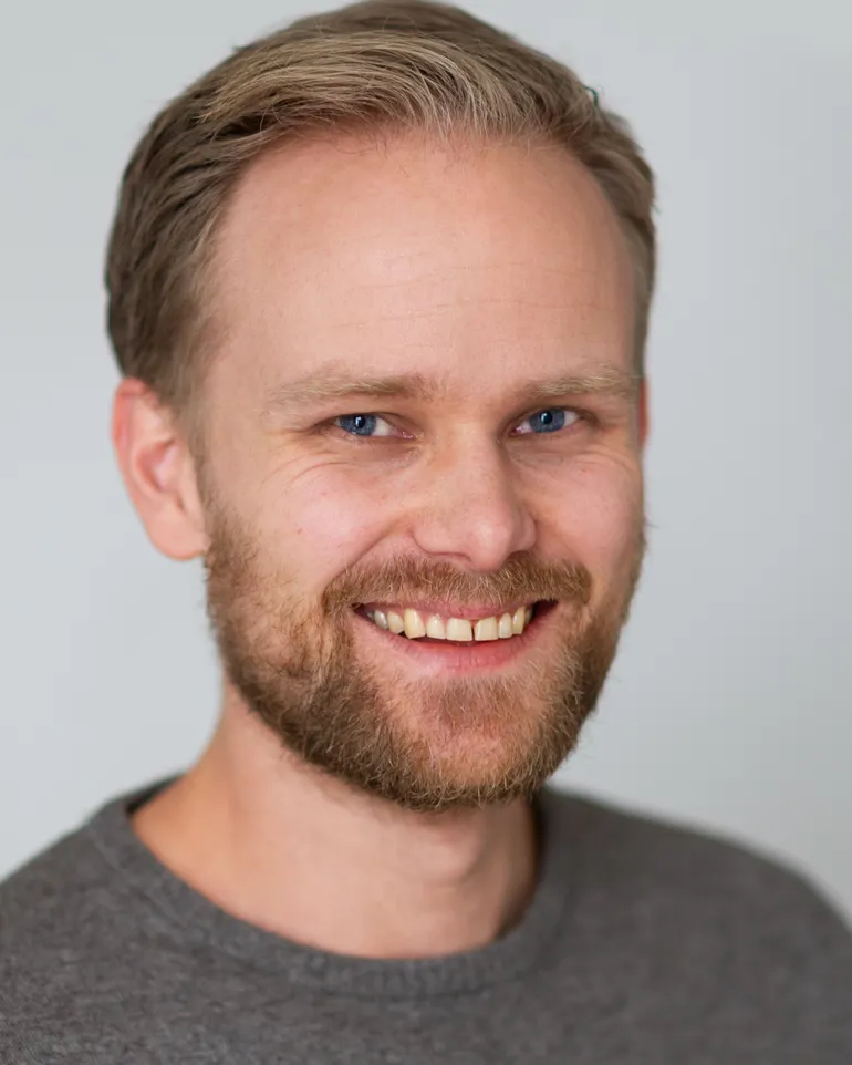 En mann med skjegg smilende
