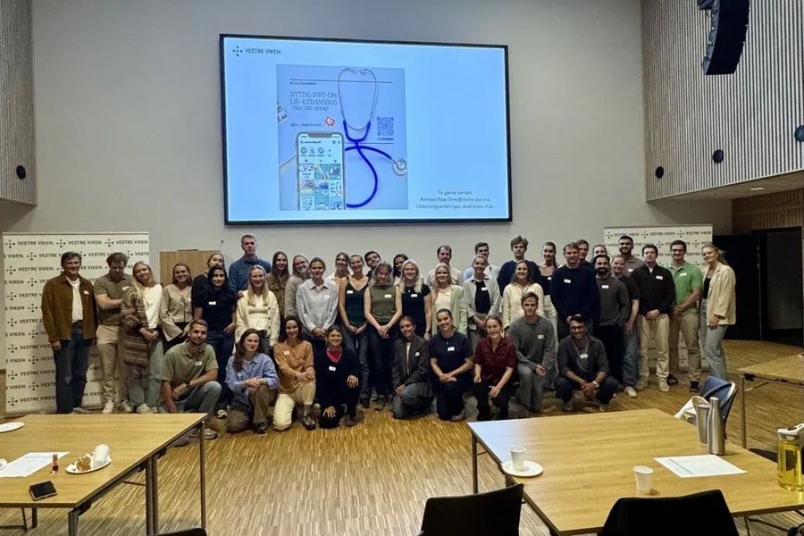 En gruppe mennesker som poserer for et bilde foran en projektorskjerm
