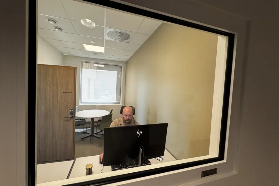 En person som sitter ved et skrivebord med en datamaskin foran seg