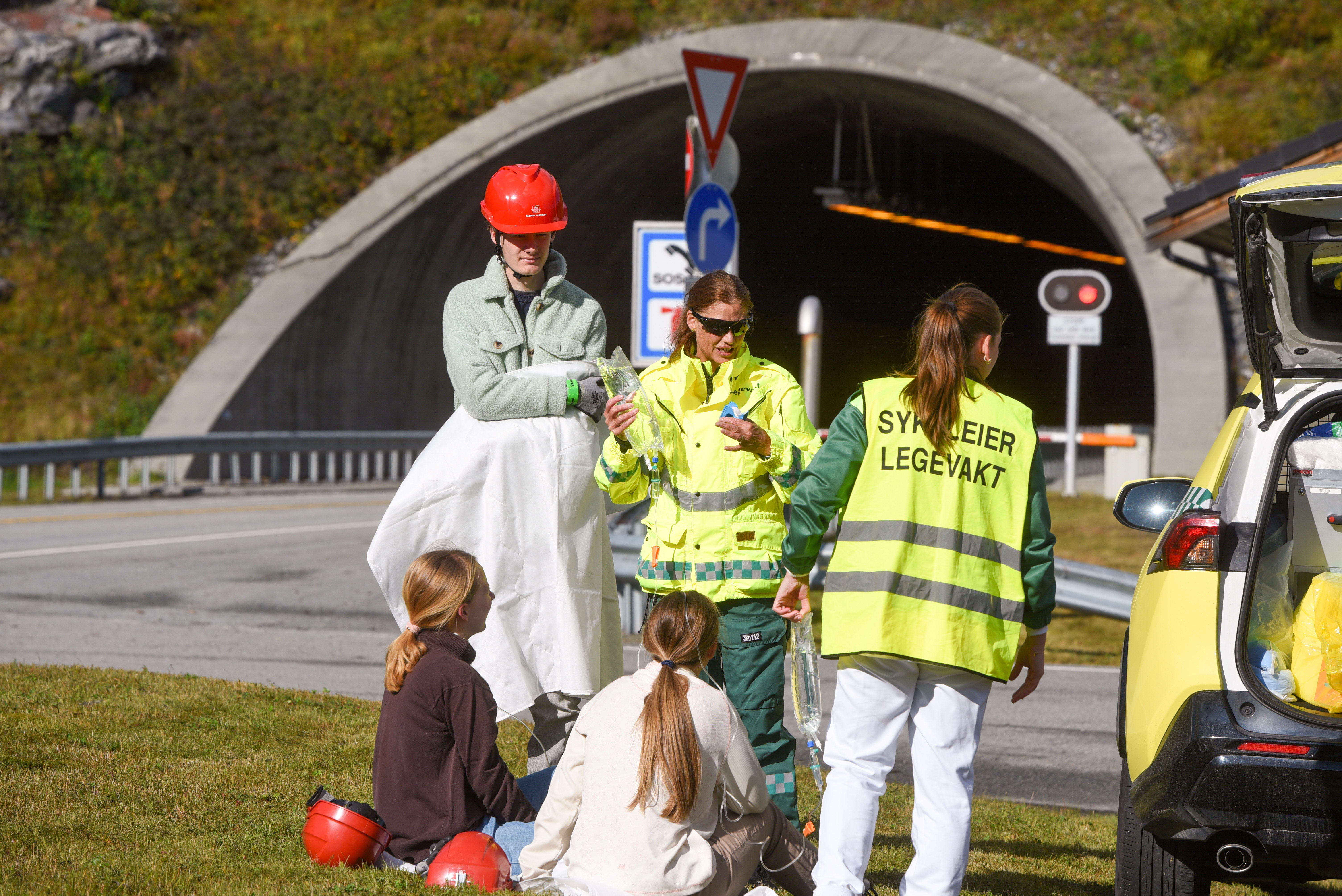 En gruppe mennesker i sikkerhetsvester står ved siden av en lastebil