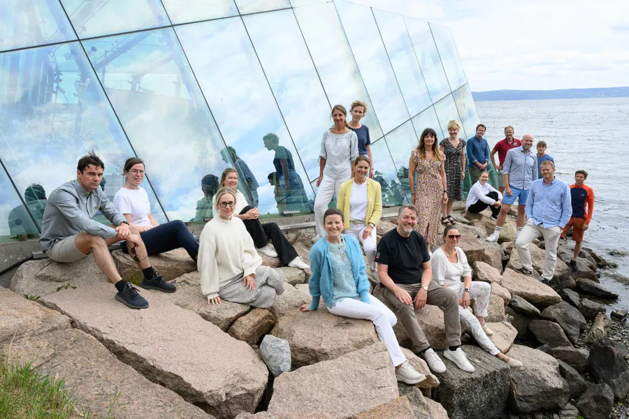 En gruppe mennesker som poserer for et bilde foran en stor glasspyramide