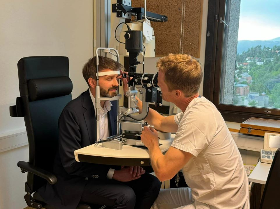 En mann som sitter ved et skrivebord med en annen mann som sitter ved et skrivebord